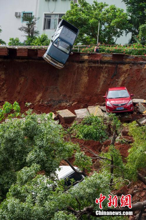 A giant sinkhole has swallowed up a parking lot in Haikou China, parking collapse haikou china landslide, landslide haikou china, sinkhole swallows parking lot china haikou, A man looks on as cars are seen stuck in a sinkhole that occurred in a parking area after heavy rainfall hit Haikou, A giant sinkhole has swallowed up a parking lot in Haikou, China. Photo: Reuter