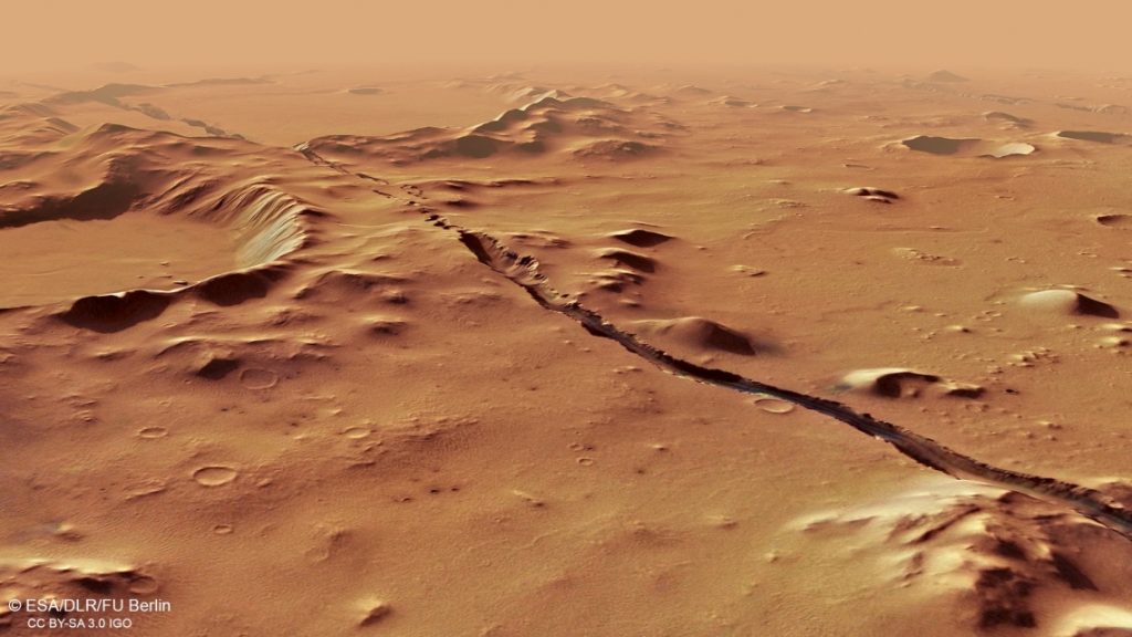 На этом снимке, сделанном орбитальным аппаратом Mars Express Европейского космического агентства, показан вид под углом к ​​одному из разломов, образующих систему Cerberus Fossae.  Разломы прорезают холмы и кратеры, указывая на их относительную молодость.