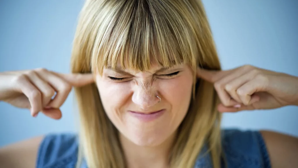 Woman covering ears as loud booms and house-shaking rumblings are reported across the United States, October 2025